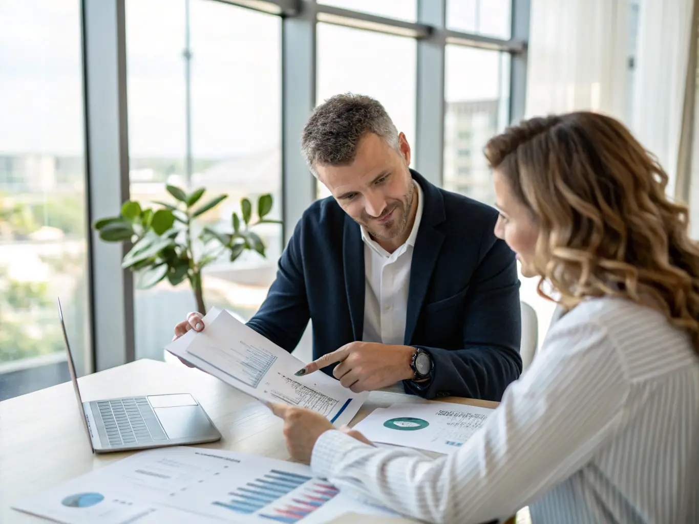 A financial advisor is reviewing investment portfolios with a client in a well-lit office, representing financial advisory services.